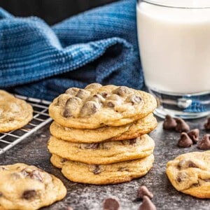 A stack of chocolate chip cookies next to a glass of milk.