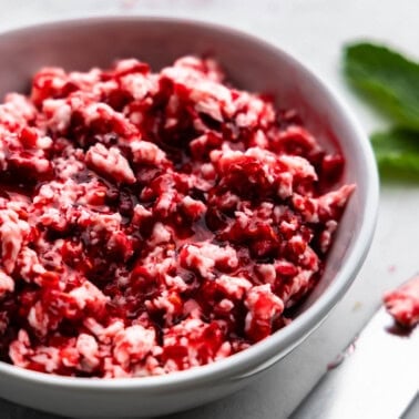 A close up view of raspberry butter in a white bowl.