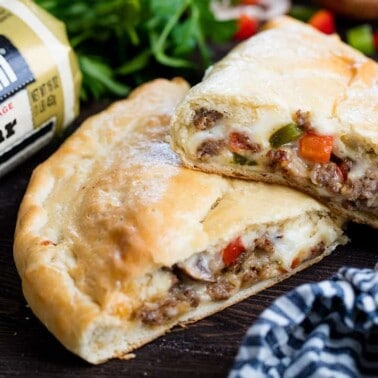 Calzone cut in half laying on a wood countertop.