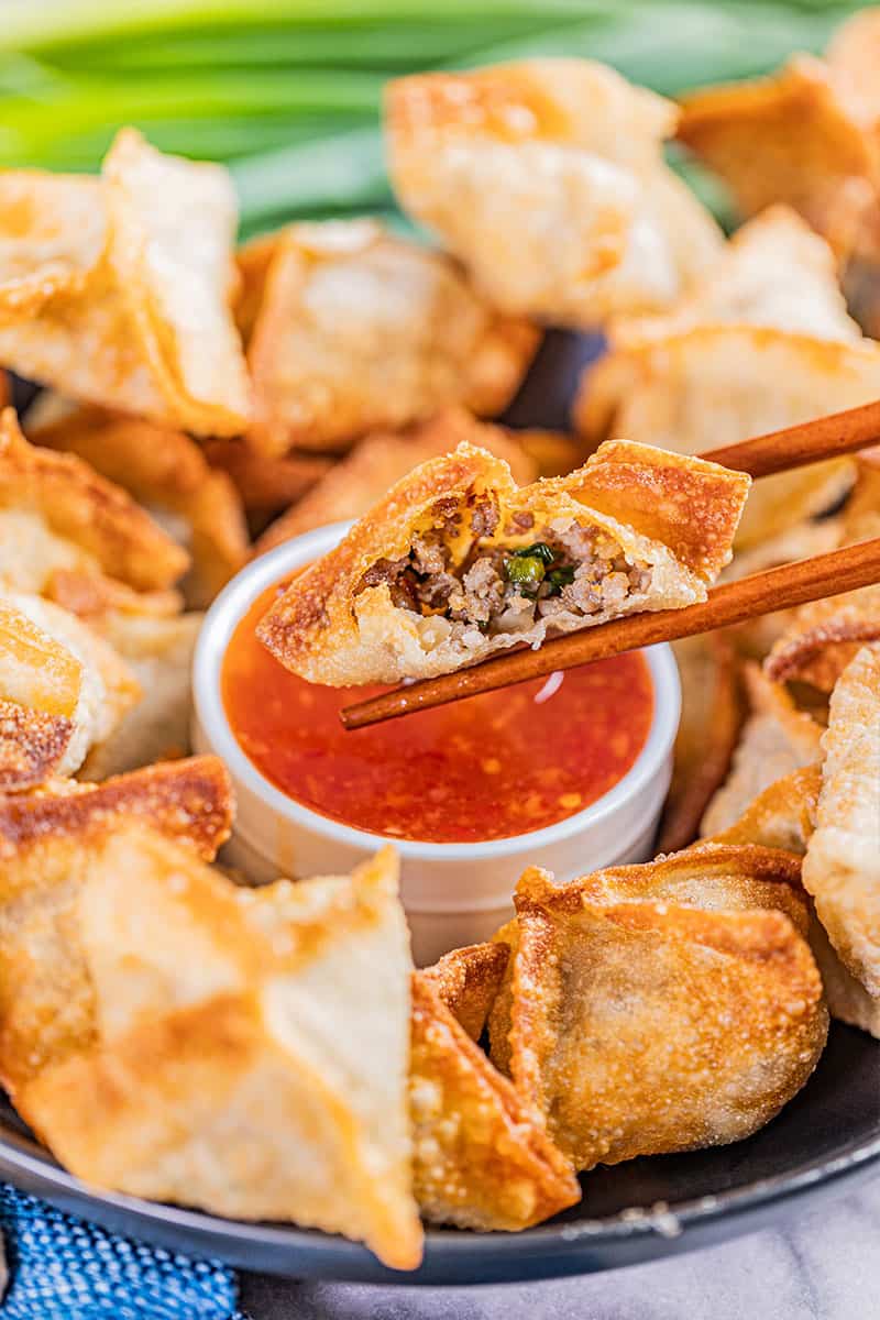 Chopsticks holding a sausage wonton.