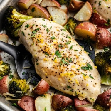 A close up view of sheet pan garlic parmesan chicken and potatoes with broccoli.