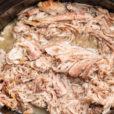 Overhead view of pulled pork in a slow cooker.