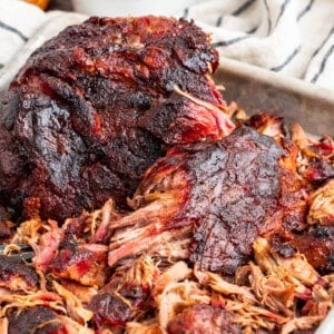 A partially shredded pork butt on a baking sheet.