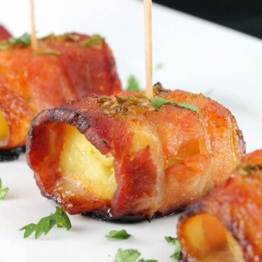 Bacon is wrapped around pineapple and glazed with a sweet and smokey sriracha-honey sauce in this spectacular appetizer.