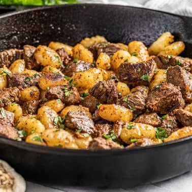 Steak bites and gnocchi in a cast iron skillet.