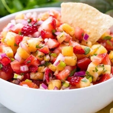 Strawberry Pineapple salsa in a white bowl with a chip in it.