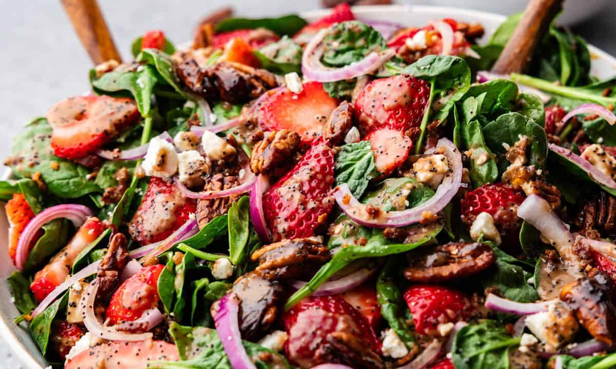 Bowl of Strawberry Spinach Salad with a wooden spoon.