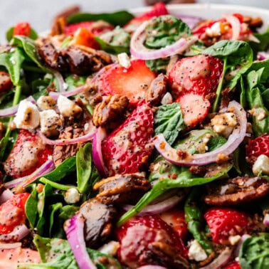 Bowl of Strawberry Spinach Salad with a wooden spoon.