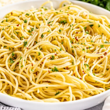 Large white serving bowl filled with olive oil pasta.