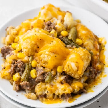 A white dinner plate with a serving of tater tot casserole.