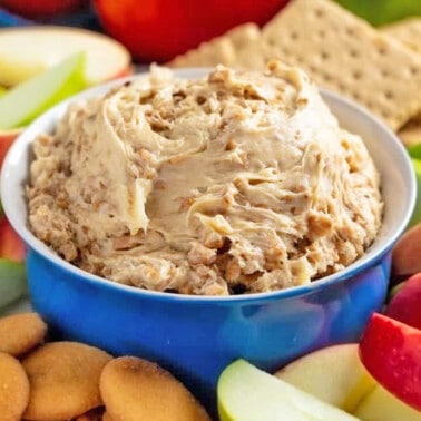 Toffee Apple Dip in a blue bowl surrounded by sliced apples, graham crackers, and Nilla wafers.