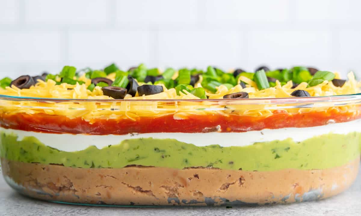 7 layer dip in a glass serving dish.