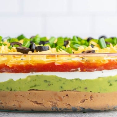 7 layer dip in a glass serving dish.