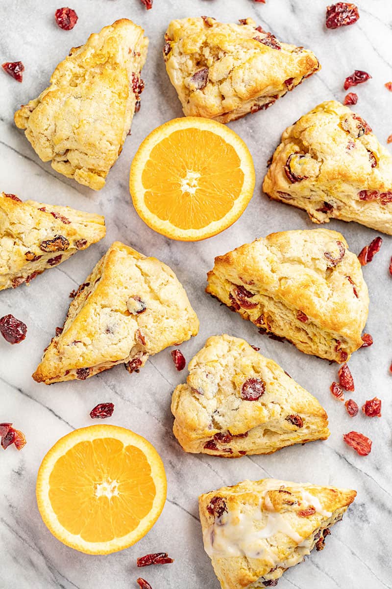 Spread of cran-orange scones with sliced oranges and cranberries.