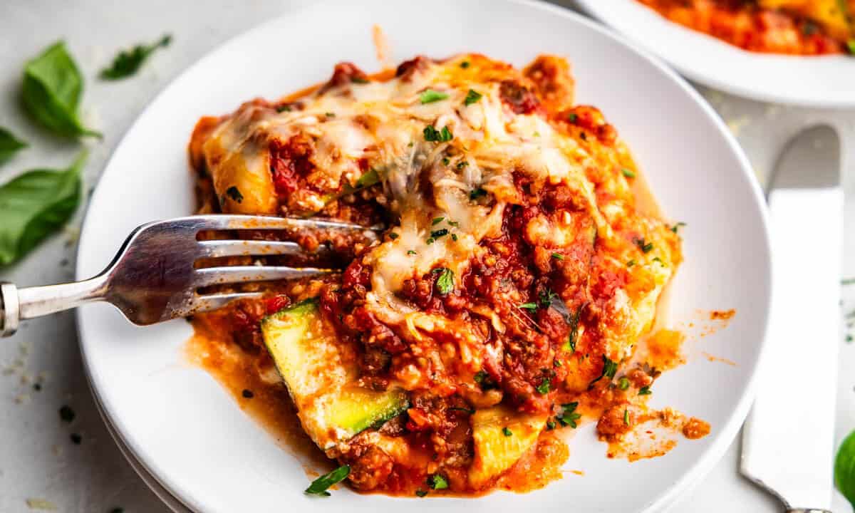 A plate with a serving of zucchini lasagna and a fork set on the plate.